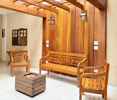 Bancos y mesa baja de madera maciza en un porche con pared de tablones