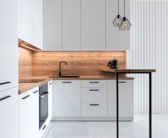 Cocina a medida blanca con frente de madera, luz LED bajo los muebles altos y barra de desayuno