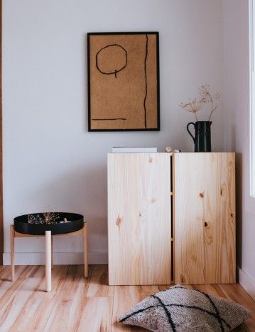 Mueble auxiliar de pino macizo con dos puertas junto a una mesita baja