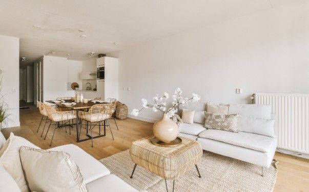 Salón comedor con mesa de madera, sillas de ratán y sofá blanco