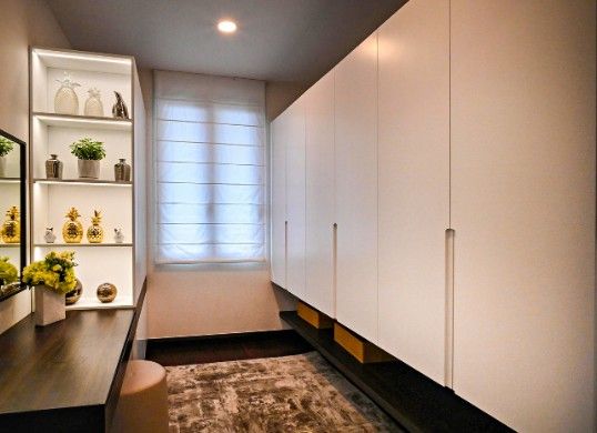 Vestidor cerrado con frentes blancos de suelo a techo y estantes iluminados